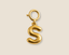 Gold letter 'S' charm on a beige background