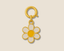 Gold and white daisy charm with meenakari colours on a beige background