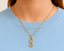 Gold infinity pendant charm on a person wearing a light blue shirt