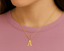 Gold necklace with a letter 'A' pendant on a pink shirt