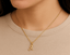 Gold necklace with a 'A' diamond pendant/ charm on a mannequin neck against a brown background