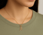 Gold necklace with a 'R' pendant/ charm worn by a person in a green shirt.