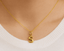 Gold necklace with a 'S' pendant on a person wearing a white sweater.